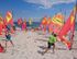 Menschen üben Windsurfen am Strand mit bunten Segeln.