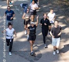 Eine Gruppe von Menschen joggt auf einem Weg im Freien.