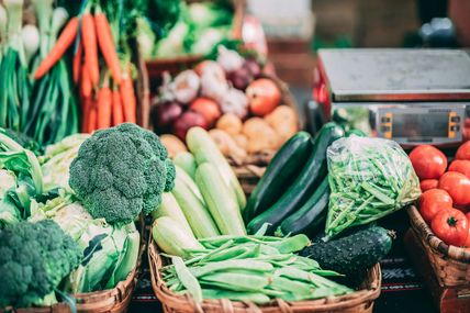 Frisches Gemüse auf einem Wochenmarkt, darunter Brokkoli, Karotten, Zucchini und Tomaten.