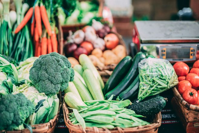 Frisches Gemüse auf einem Wochenmarkt, darunter Brokkoli, Karotten, Zucchini und Tomaten.