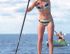 Eine Frau steht auf einem Stand-Up-Paddleboard auf dem Wasser, während eine andere Person in einem Kajak im Hintergrund paddelt.